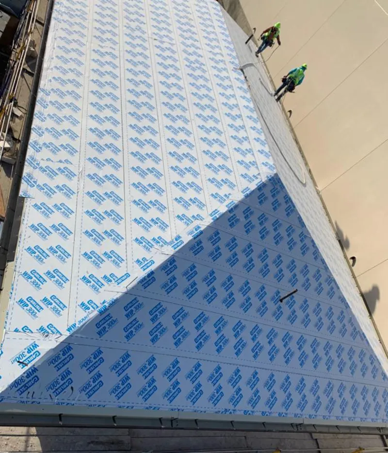 Professional roofers installing underlayment on a metal roof in Watchung